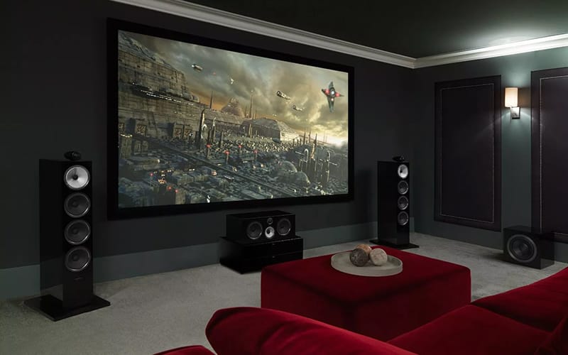 Home cinema room with a large projector screen, floorstanding speakers and red seating