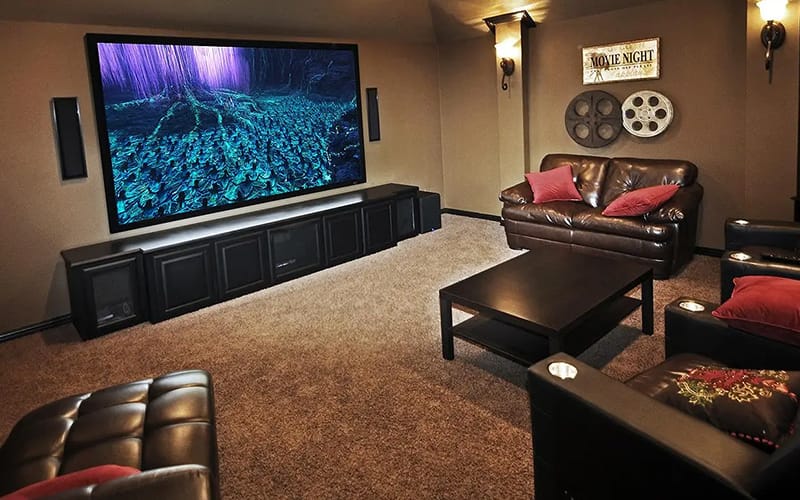 Home theatre room with a large screen, in-wall speakers, leather seating and a media cabinet